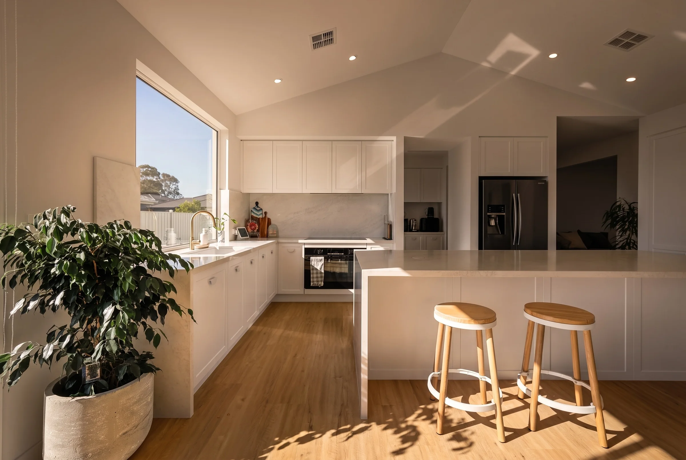 Kitchen with a stone island and timber floors under a raked ceiling