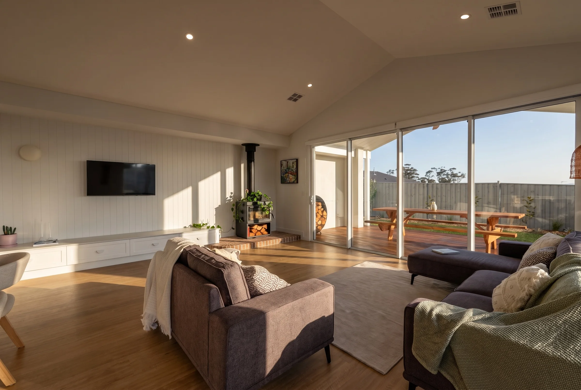Open-plan living room with a wood fire and doors to the deck